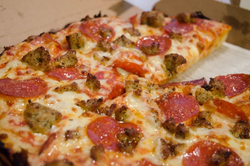 Photo of a Domino's pan crust pizza with pepperoni and sausage.